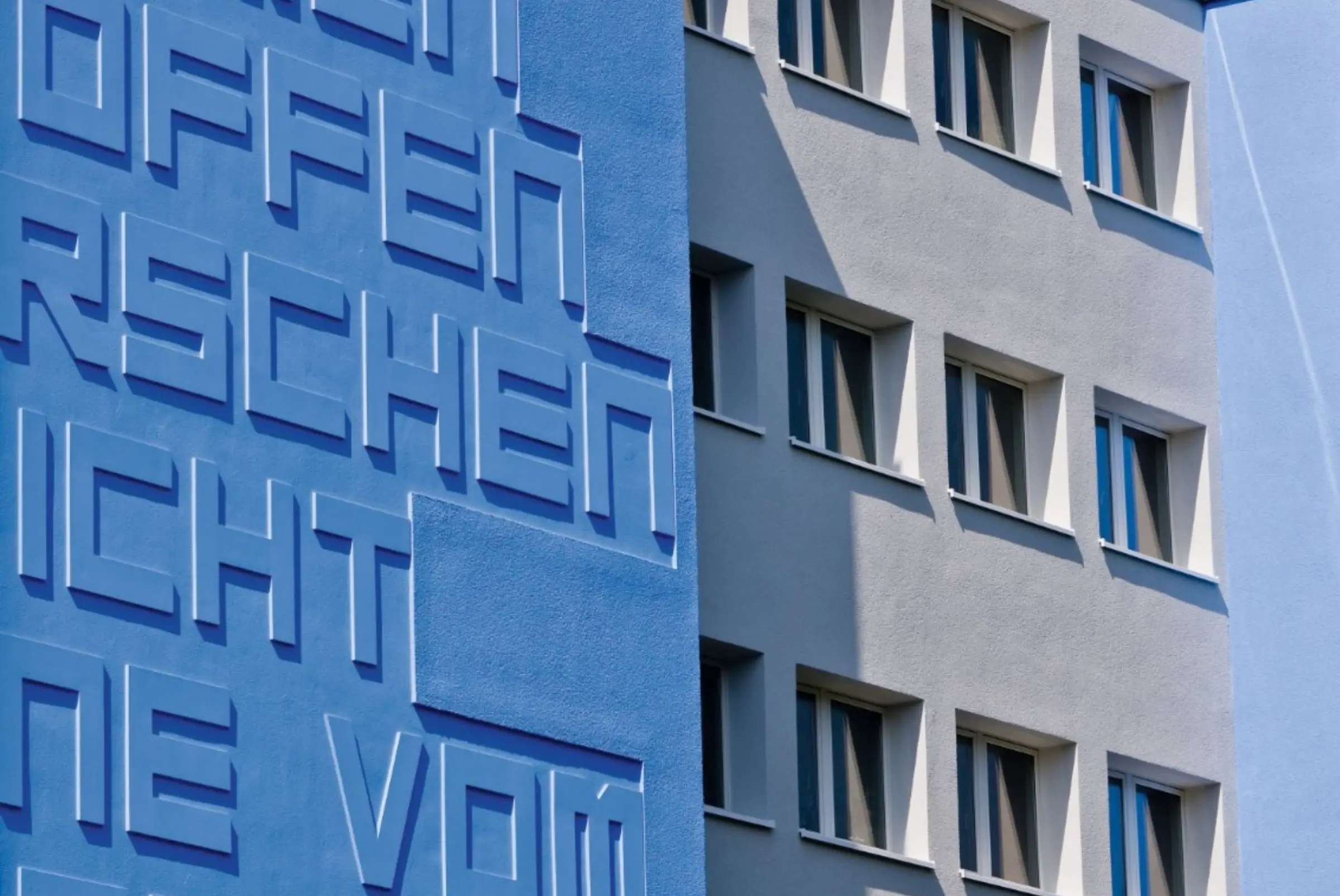 Vista esterna di edificio residenziale con facciata blu arricchita da elementi architettonici 