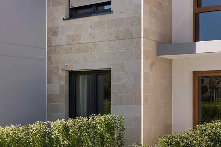 Detailansicht einer beigen Natursteinfassade, mit WDVS von Sto gedämmte Natursteinfassade: StoStone